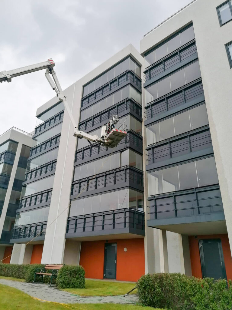 Körfubíll notaður til að þvo svalalokanir og gler á fjölbýlishúsi.