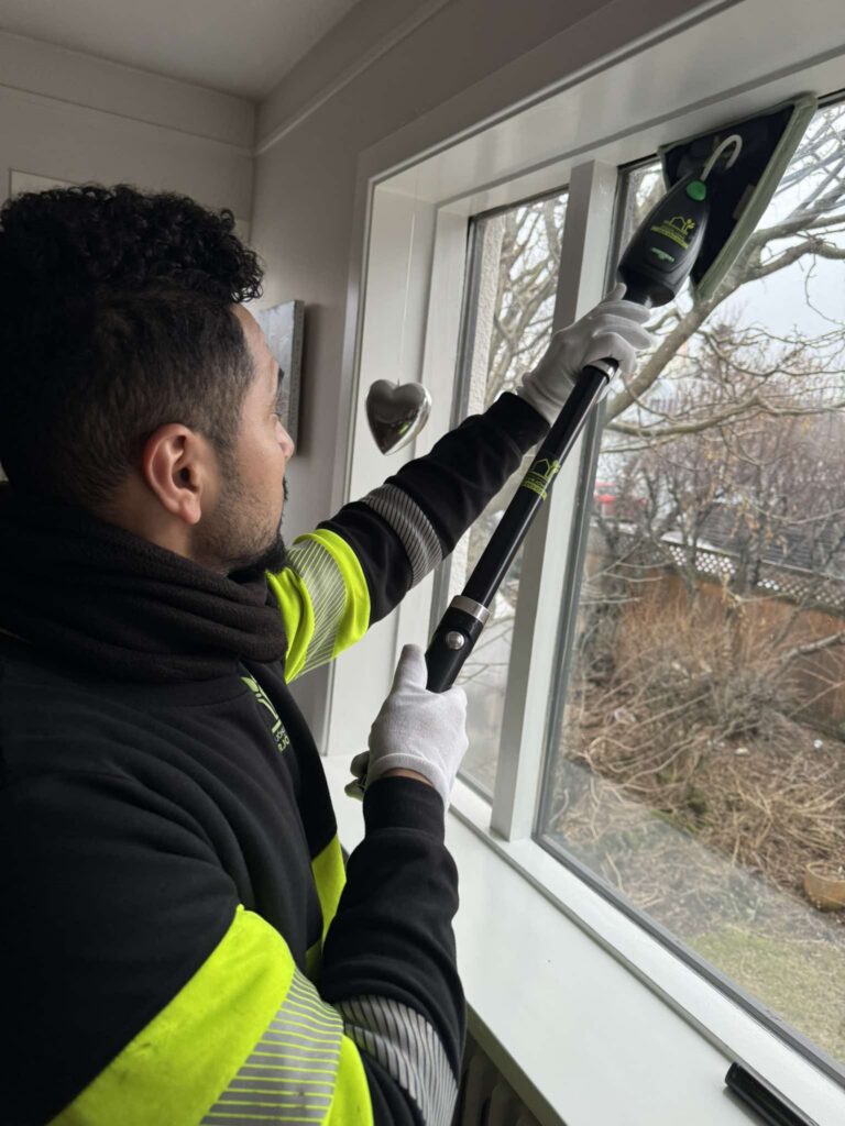 Starfsmaður að þvo glugga að innan með sérhæfðum búnaði sem skilur ekki eftir sig rákir.