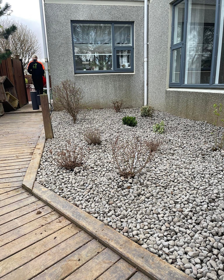 Fallegur frágangur á garði þar sem möl og trépallur mynda snyrtilega heild