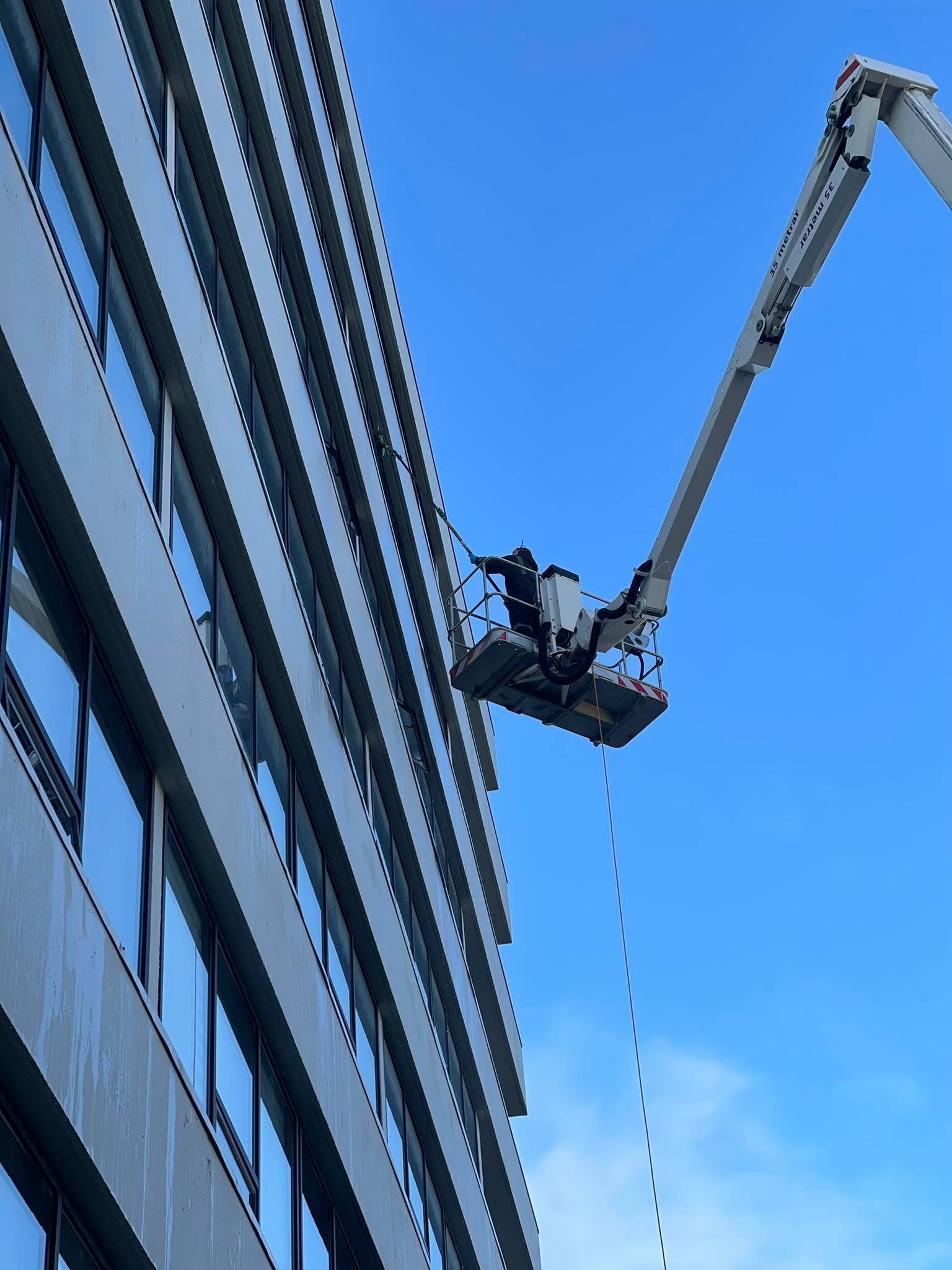 Gluggaþvottur á hárri skrifstofubyggingu með stórri lyftu.