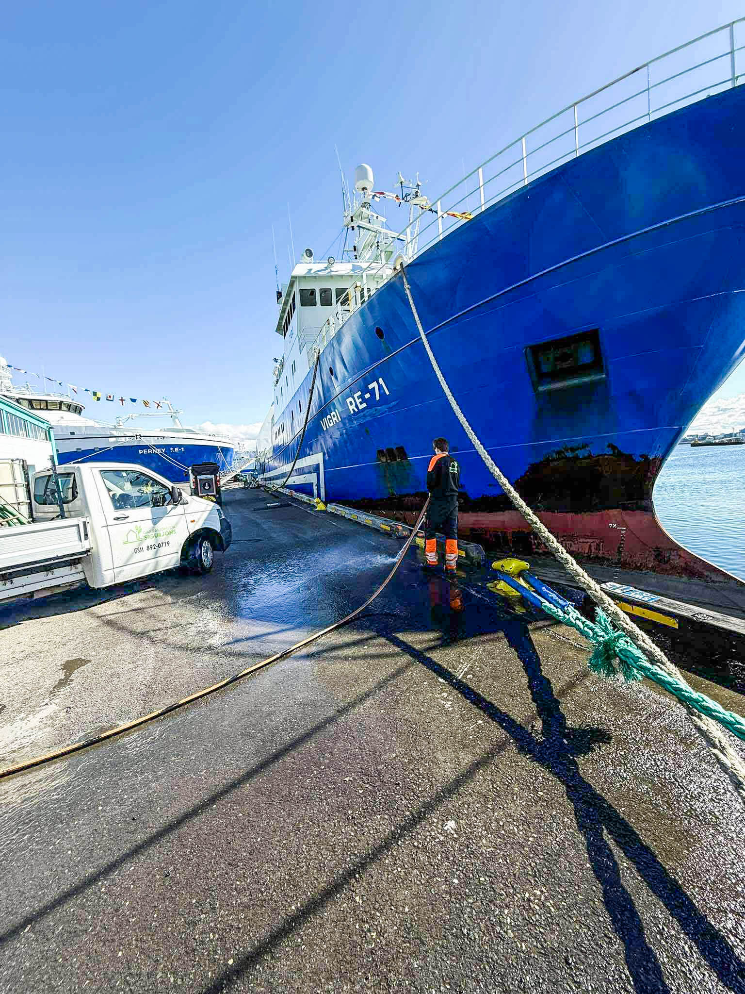 Starfsmaður að háþrýstiþvo skipið Vigri RE-71 við bryggju. Sérhæfð þrif á skipum og hafnarmannvirkjum.