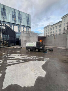 Götusópari að þrífa steypt plan við nýlega byggingu. Hreinsun á byggingarsvæðum og stéttum.