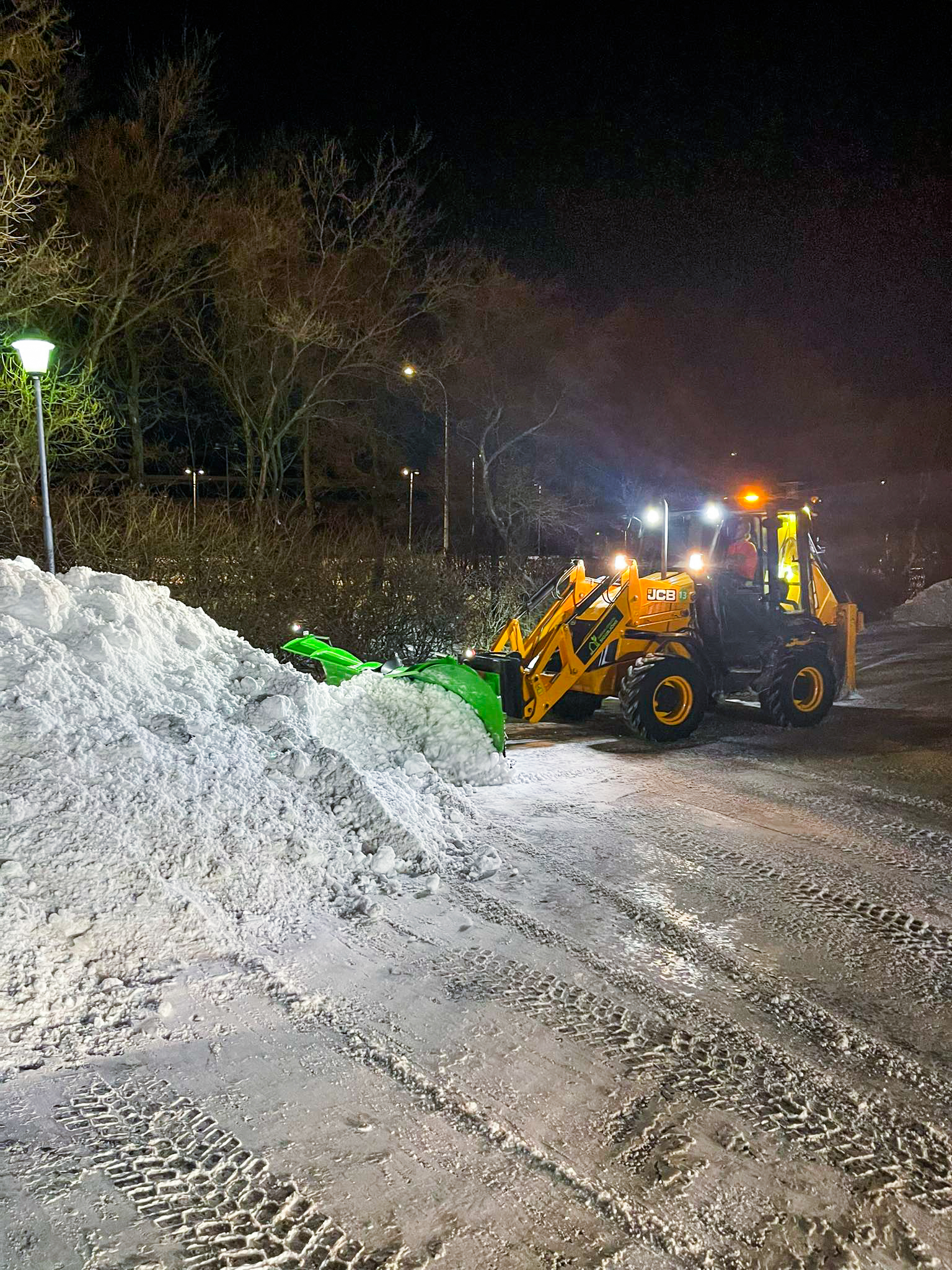 Snjómokstur að næturlagi. Traktorsgrafa að ryðja bílaplan og tryggja aðgengi fyrir morguninn.