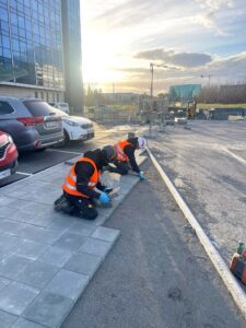 Fagmenn að leggja stórar gangstéttarhellur við atvinnuhúsnæði.