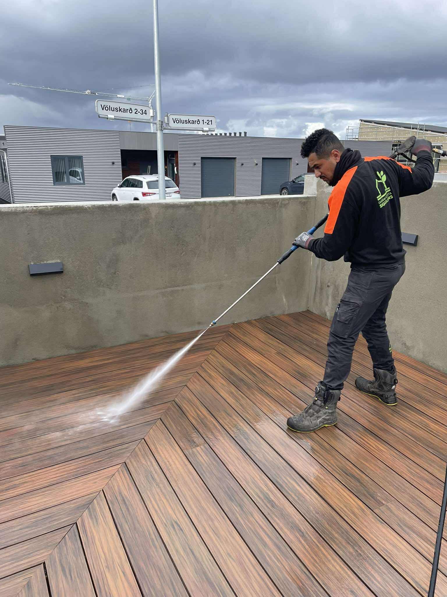 Starfsmaður Garðaþjónustu Sigurjóns að háþrýstiþvo viðarpall af fagmennsku