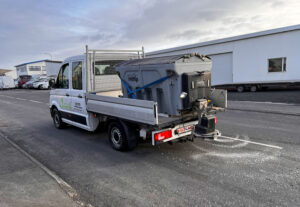 Hvítur vörubíll frá Garðaþjónustu Sigurjóns með Hilltip búnað dreifir salti fyrir hálkuvarnir á vegi.