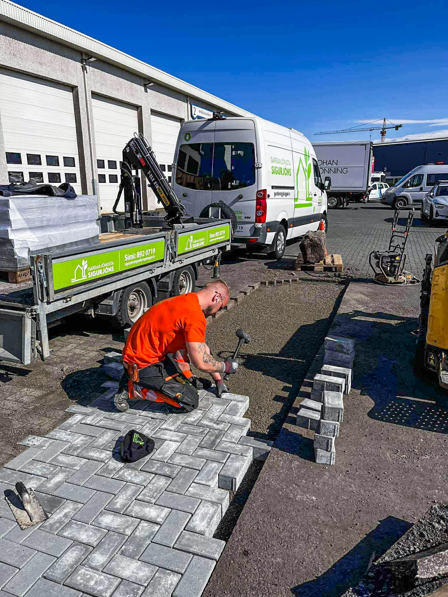 Starfsmaður að jafna sandundirlag og undirbúa fyrir hellulögn.